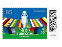 Pokal vor bunter Stadionkulisse unter blauem Himmel mit Veranstaltungslogo