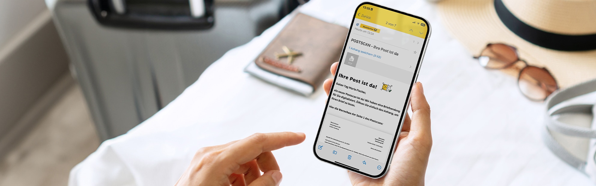 Handy mit Postscan Nachricht im Vordergrund, Reiseutensilien im Hintergrund