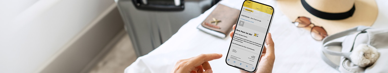 Handy mit Postscan Nachricht im Vordergrund, Reiseutensilien im Hintergrund
