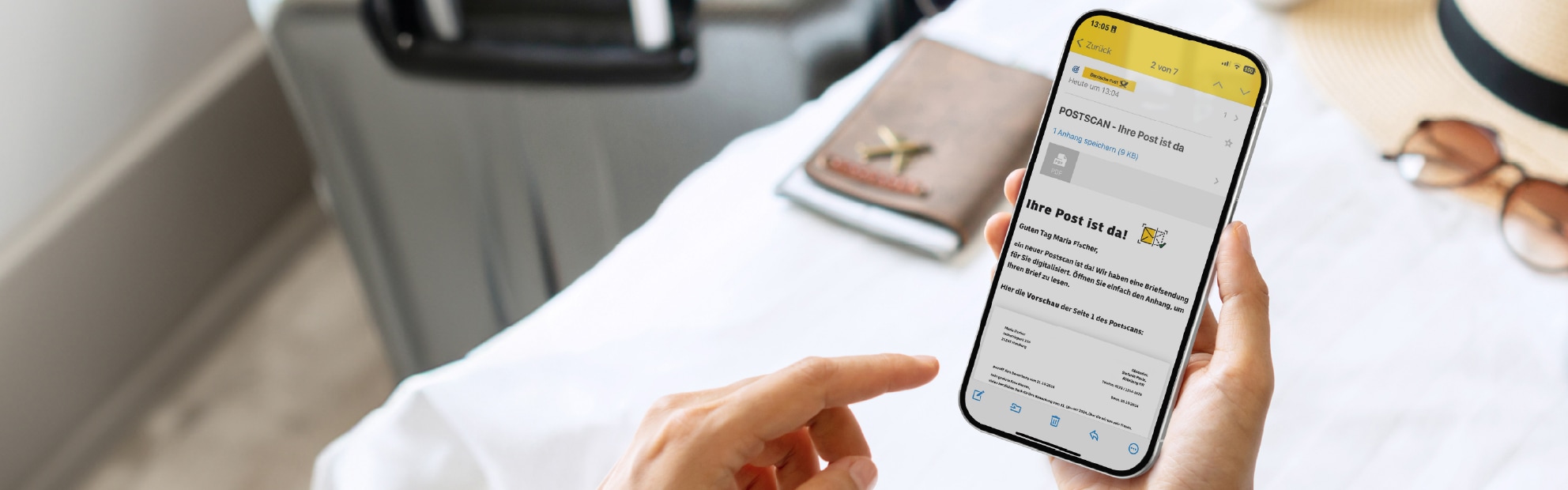 Handy mit Postscan Nachricht im Vordergrund, Reiseutensilien im Hintergrund