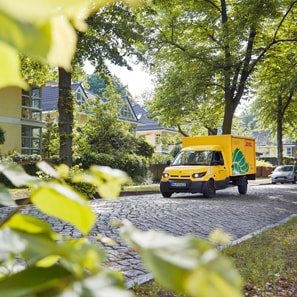 Zustellfahrzeug mit Logo GoGreen Plus f�hrt in Wohnallee entlang